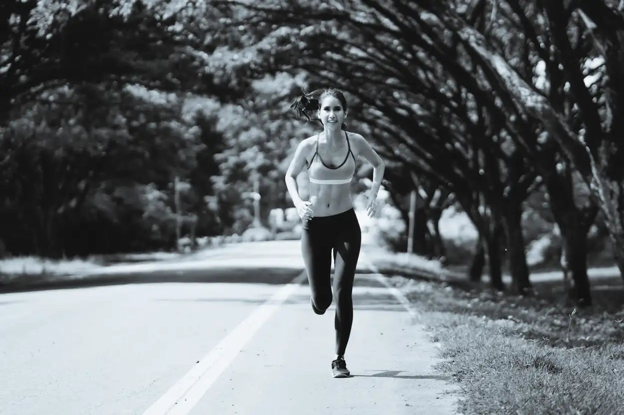 Woman running on a road with trees lining the sides