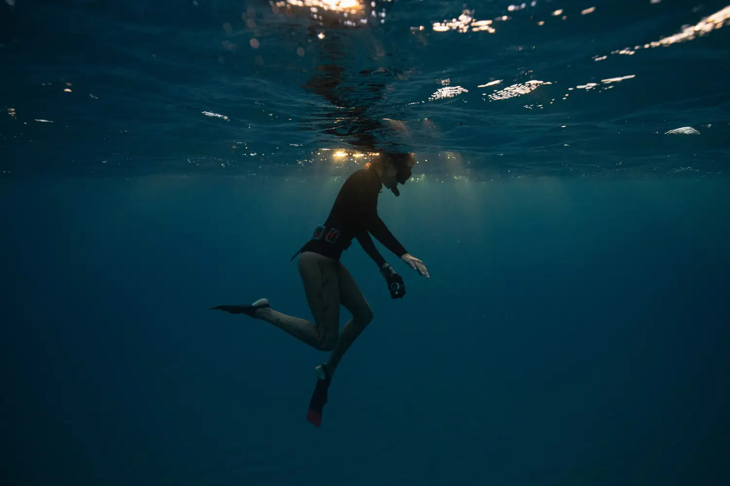 Person snorkeling underwater with sunlight filtering through the water.